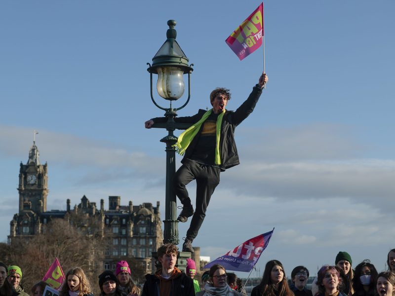 Person climbing light post holding a flag.